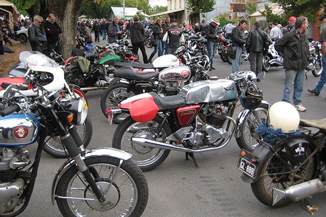 Street packed with old bikes and people.