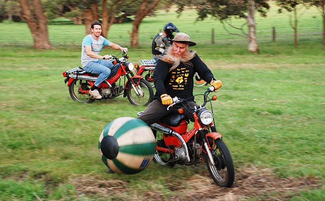 Bruce on a postie boots the soccer ball.